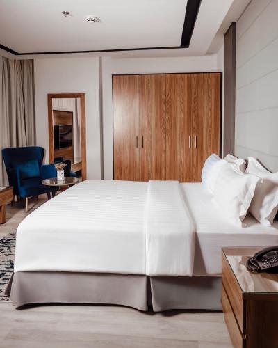 a bedroom with a large white bed and a blue chair at Villa Misk Alkhobar in Al Khobar