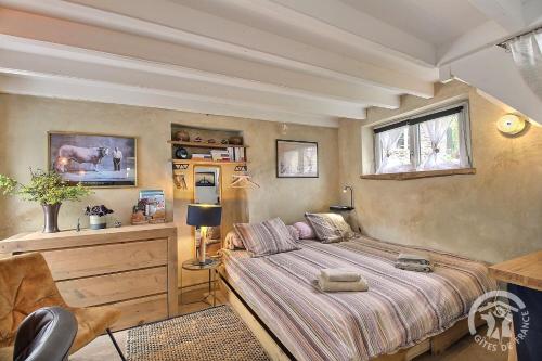 a bedroom with a bed and a desk and a window at La petite maison de dom in Pleslin-Trigavou