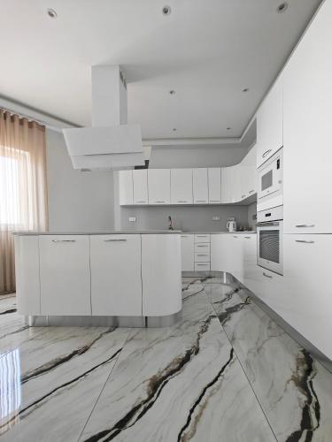 a kitchen with white cabinets and marble floors at BluSky in Safi