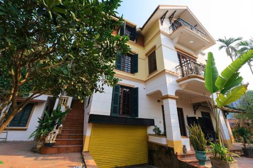 a house with a yellow garage in front of it at Vườn Tùng RiverSide retreat & Villa - KDT ECOPARK in Kim Quan