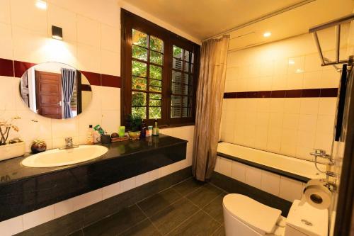 a bathroom with a sink and a toilet and a mirror at Vườn Tùng RiverSide retreat & Villa - KDT ECOPARK in Kim Quan