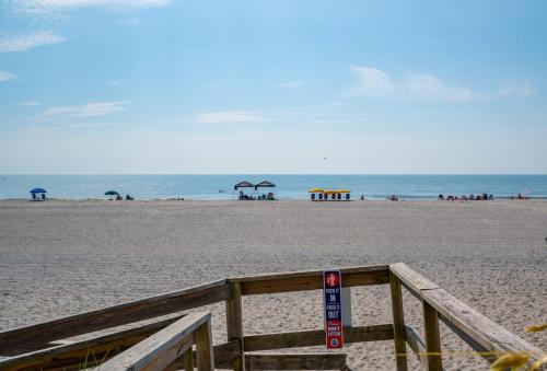 einen Sandstrand mit einer hölzernen Promenade und dem Meer in der Unterkunft Waterfront condo one block to Oceanfront in Sea Breeze