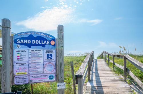 ein Schild auf einem Holzsteg am Strand in der Unterkunft Waterfront condo one block to Oceanfront in Sea Breeze