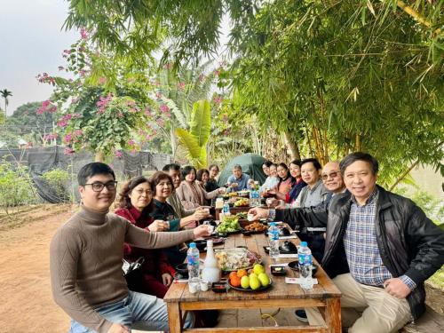 a group of people sitting around a wooden table at Vườn Tùng RiverSide retreat & Villa - KDT ECOPARK in Kim Quan