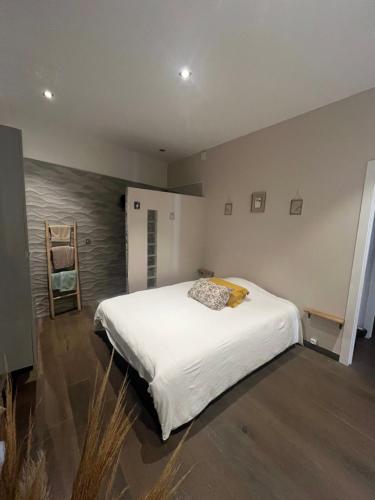 une chambre avec un grand lit blanc et une chaise dans l'établissement Appartement cœur de ville Ajaccio, à La Celle-sous-Gouzon