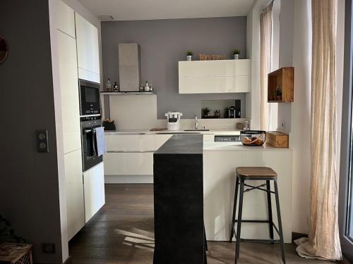 une cuisine avec un comptoir noir et blanc et un tabouret dans l'établissement Appartement cœur de ville Ajaccio, à La Celle-sous-Gouzon