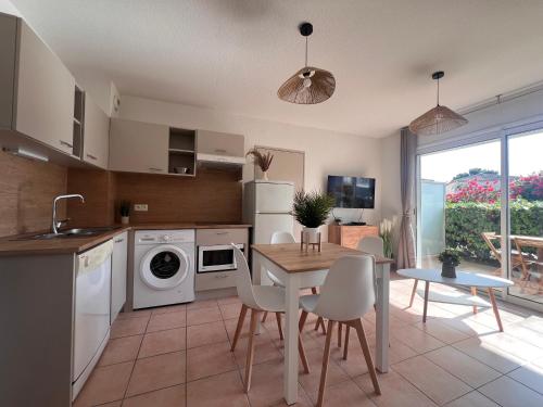 une cuisine et une salle à manger avec une table et des chaises dans l'établissement Apparemment RdC climatisé avec piscine, terrasse et parking - App 1502, à Gruissan