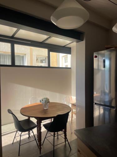 une cuisine avec une table, des chaises et un réfrigérateur dans l'établissement Maison de ville avec jardin, au Mans