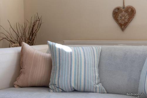 two pillows on a couch with a heart on the wall at Harmony Undercroft in North Berwick