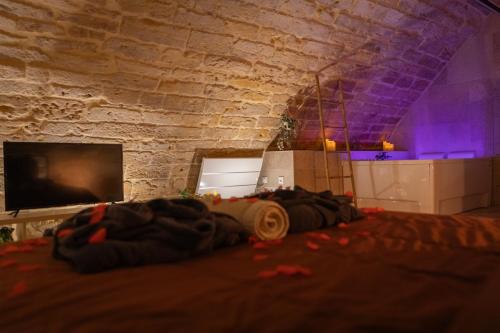 a bed in a room with a stone wall at Le Troglochill in Belvès