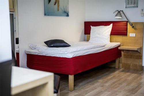 a small bed in a room with a red headboard at Scandic The Mayor in Aarhus