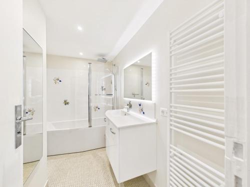 une salle de bain blanche avec un lavabo et une douche dans l'établissement 120 m de la plage- Appartement pour 4 - balcon, à La Baule