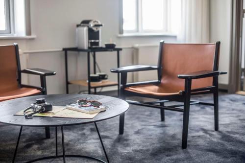 a room with three chairs and a table with a book at Scandic The Mayor in Aarhus