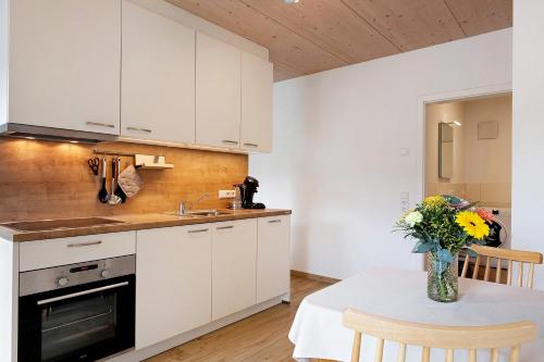 a kitchen with white cabinets and a table with a vase of flowers at Wanderlust in Todtnau