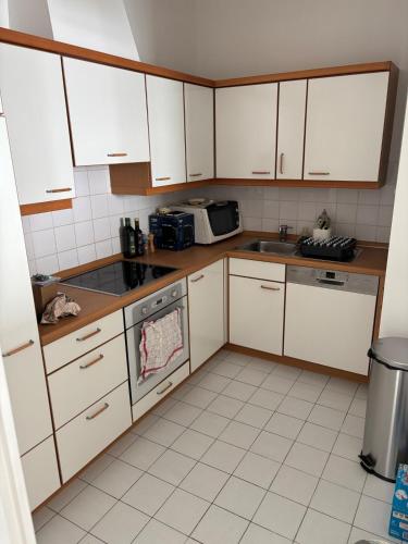 une cuisine avec des armoires blanches, un évier et un micro-ondes dans l'établissement Celtic, à Trébeurden