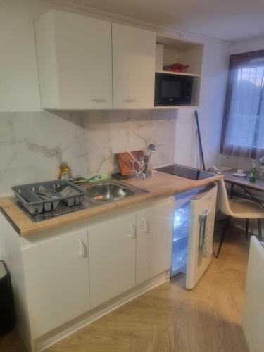 une cuisine avec des armoires blanches et un évier dans l'établissement Platinum cottage, à Villeneuve d'Ascq