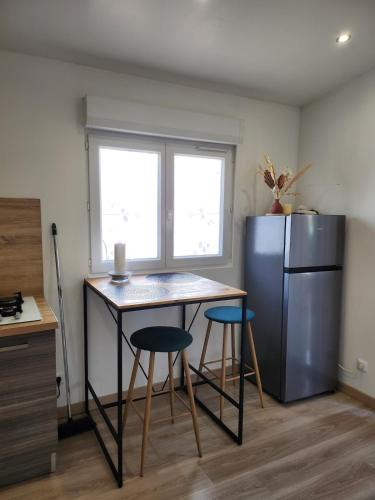 a kitchen with a table and two stools and a refrigerator at Charmant studio équipé à Elbeuf in Elbeuf