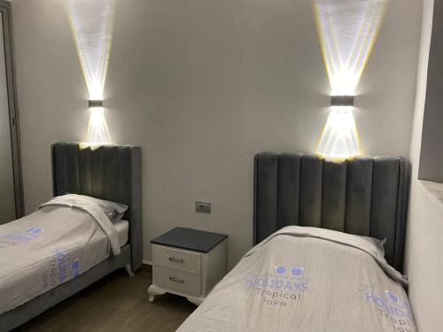 a bedroom with two beds and lights on the wall at Luxury beach apartment in Kerkennah in Ouled Kacem