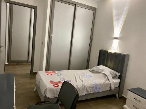 a small bedroom with a bed and a chair at Luxury beach apartment in Kerkennah in Ouled Kacem