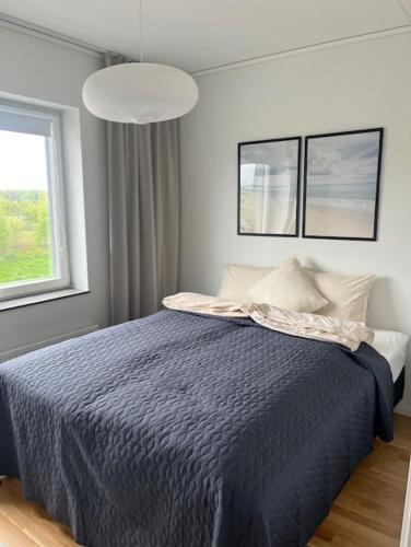 a bedroom with a bed with a blue comforter and a window at Elme Apartment 2 in Växjö