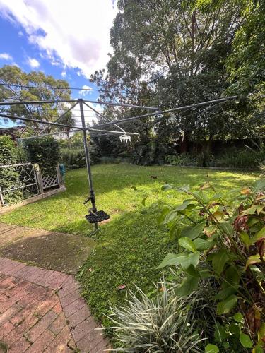 a garden with a swing in the grass at Peaceful Queen Room in Cozy Garden House - KV4 in Kellyville