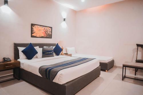 a bedroom with a large bed with blue pillows at The Garden Hotel in Islamabad