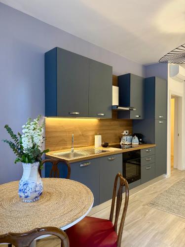 a kitchen with blue cabinets and a table with a vase of flowers at LR Deluxe Apartments - Casa Holi in Pero