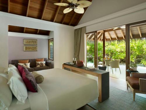 a bedroom with a bed and a living room at Dusit Thani Maldives - 50 percent discount on transfers for stays until 20 Dec 2025 in Baa Atoll