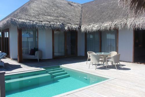 a resort with a table and chairs and a swimming pool at Dusit Thani Maldives - 50 percent discount on transfers for stays until 20 Dec 2025 in Baa Atoll