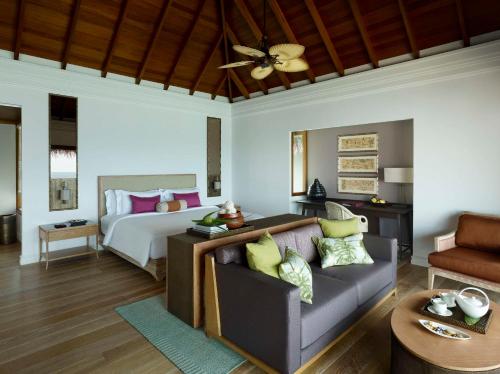 a bedroom with a bed and a couch in a room at Dusit Thani Maldives - 50 percent discount on transfers for stays until 20 Dec 2025 in Baa Atoll