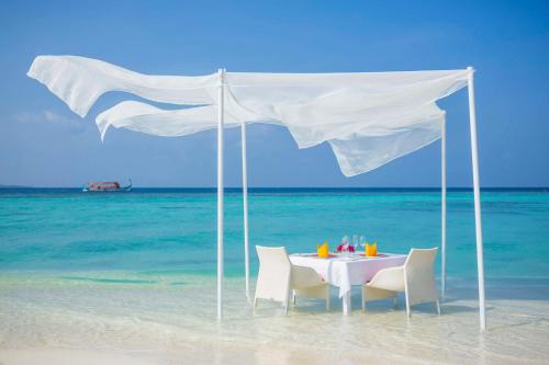 a table and chairs under a white tent on the beach at Dusit Thani Maldives - 50 percent discount on transfers for stays until 20 Dec 2025 in Baa Atoll