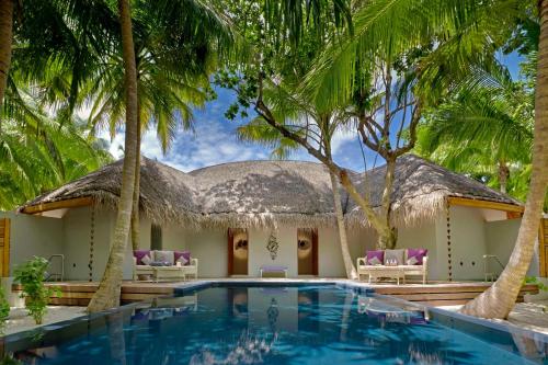 a resort with a swimming pool and palm trees at Dusit Thani Maldives - 50 percent discount on transfers for stays until 20 Dec 2025 in Baa Atoll