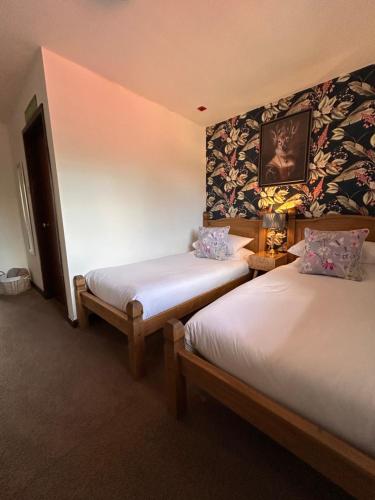 two twin beds in a room with a wall with flowers at Castle Inn in Knighton