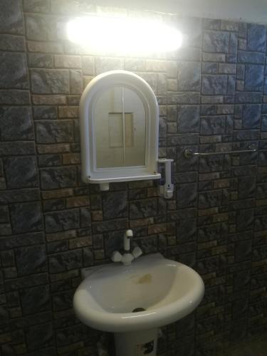 a bathroom with a sink with a light above it at Saya Hostel and Hotel in Karachi