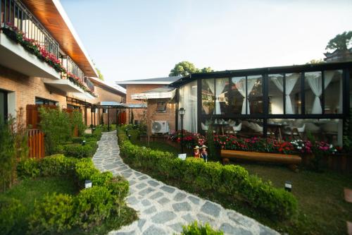 a house with a garden with flowers and a walkway at Pousada Santa Felicidade in Campos do Jordão