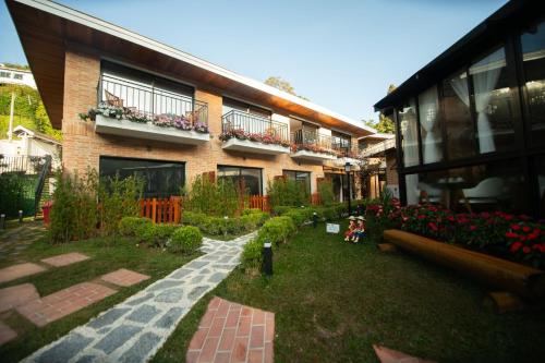 a house with a garden in front of it at Pousada Santa Felicidade in Campos do Jordão