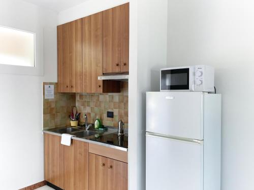 a kitchen with a white refrigerator and wooden cabinets at Smart Residence Aviano in Aviano