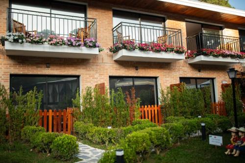 a brick building with flower boxes on its windows at Pousada Santa Felicidade in Campos do Jordão