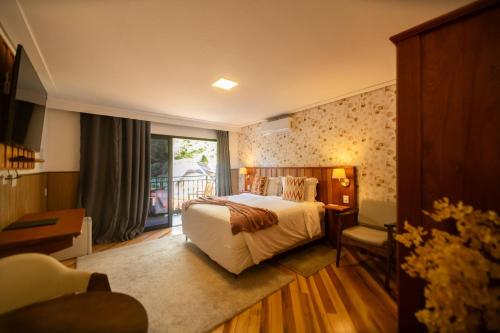 a hotel room with a bed and a balcony at Pousada Santa Felicidade in Campos do Jordão