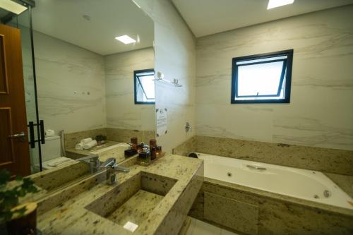 a large bathroom with a tub and a sink at Pousada Santa Felicidade in Campos do Jordão