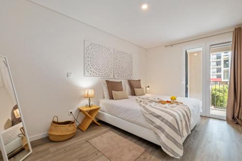 a white bedroom with a bed and a large window at Carmo Heritage Apartments in Funchal