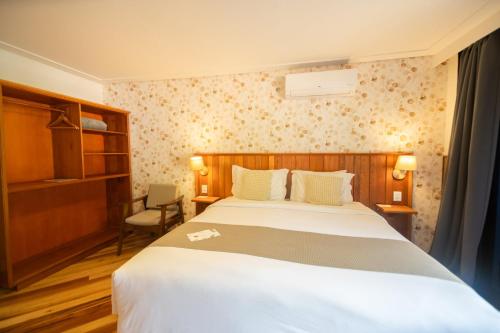 a bedroom with a large bed and a chair at Pousada Santa Felicidade in Campos do Jordão
