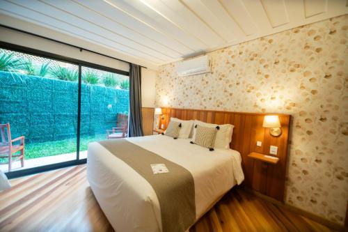 a bedroom with a large bed and a large window at Pousada Santa Felicidade in Campos do Jordão