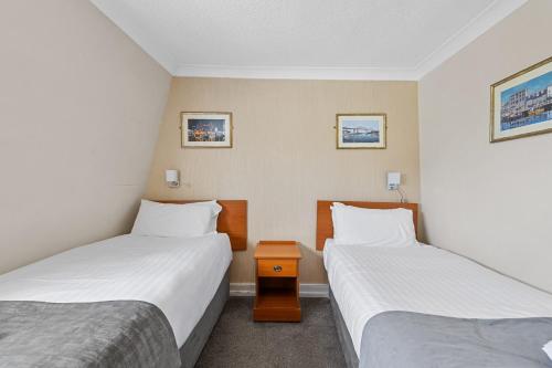 a room with two beds and a nightstand between them at Invicta Hotel Plymouth in Plymouth