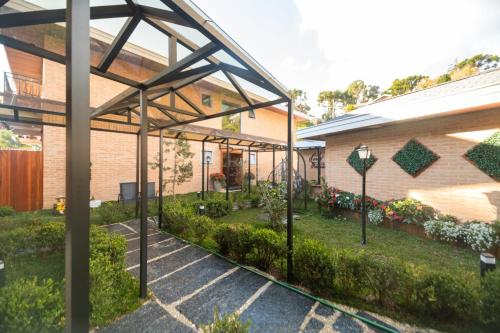 a garden outside a brick building with plants at Pousada Santa Felicidade in Campos do Jordão