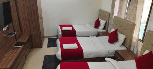 a room with two beds with red and white sheets at The Paramant Near Delhi IGI Airport in New Delhi