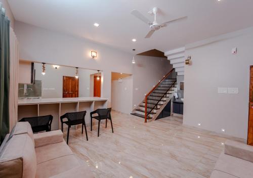 a living room with a staircase and a table and chairs at Oasis Apartment with Pool in Vythiri in Vythiri