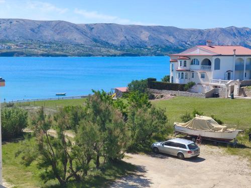 a car parked in front of a house with a boat at Tonino apartments in Pag