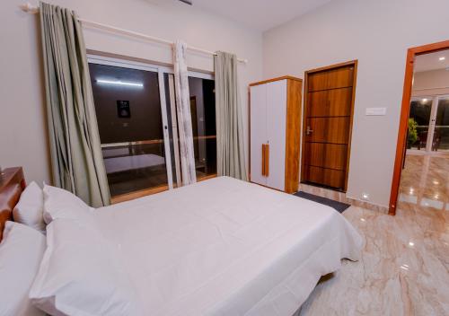a bedroom with a white bed and a large window at Oasis Apartment with Pool in Vythiri in Vythiri