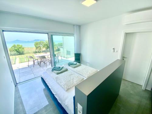 a bedroom with a bed and a balcony with a table at Villapark Apartman B2 Fonyód in Fonyód